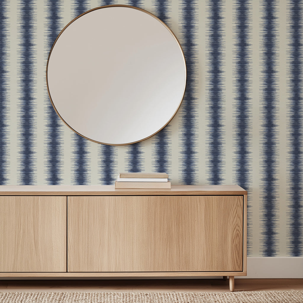 Wooden cabinet with a round mirror against a striped wallpaper wall.  Abstract stripe wallpaper pattern with textured, irregular vertical bands that create organic movement and a modern, layered look inspired by natural rhythm. Blue white ivory, Les Touches